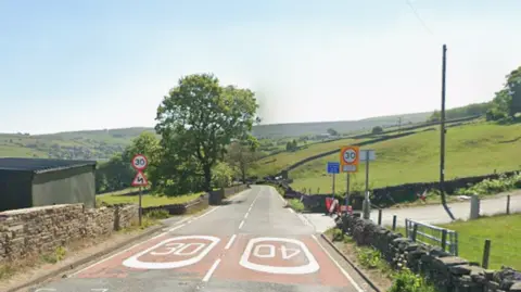 A rural road junction where the speed limit changes from 40 to 30. There are rolling green fields in the distance