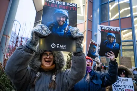 AFP via Getty Images People shout and wear warm coats and hats as they hold up photos of Alex Pretti with signs reading 'justice for Alex Pretti' in Minnesota on Monday.