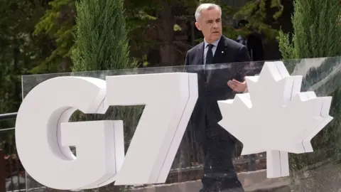 PA Media Canadian Prime Minister Mark Carney walks by a large sign for the G7 summit in Kananaskis during the G7 Leaders' Summit in Alberta, Canada