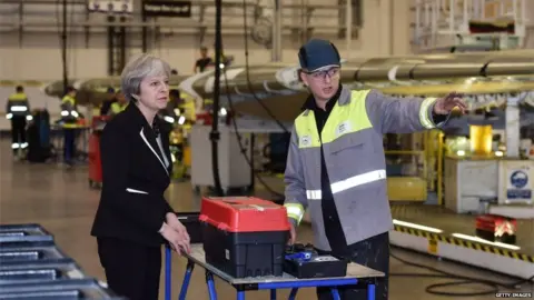 Getty Images Prime Minister Theresa May speaks to a worker during a visit to the Belfast Bombardier factory in February 2018