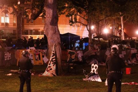 Two police officers stand in front of a pro-Palestine encampment at USC