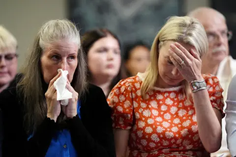 Jacob King/PA Wire Sarah Hawkins holds a tissue to her face and appears tearful. Sarah Hawkins, sitting next to her, holds her hand to her forehead.