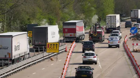 Queues of lorries and other vehicles travelling away from the camera on a motorway