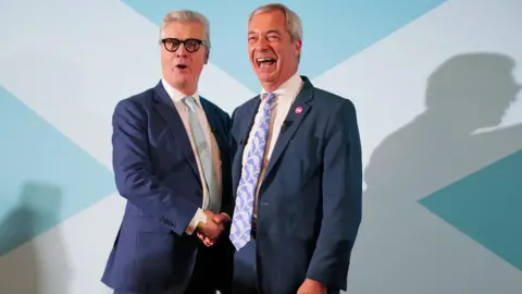 PA Media Malcolm Offord, left, shaking hands with Nigel Farage, right, in front of a blue and white saltire background.