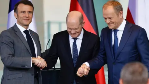 HANNIBAL HANSCHKE/EPA-EFE (L-R) French President Emmanuel Macron, German Chancellor Olaf Scholz and Poland's Prime Minister Donald Tusk shake hands after a news conference at the Chancellery in Berlin