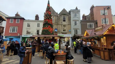 Police officers in high visibility jackets are seen dotted around a crowd at a Christmas market in Oxford city centre