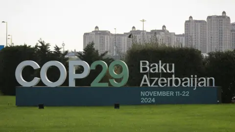 Reuters COP29 sign with a backdrop of the cityscape in Baku, Azerbaijan