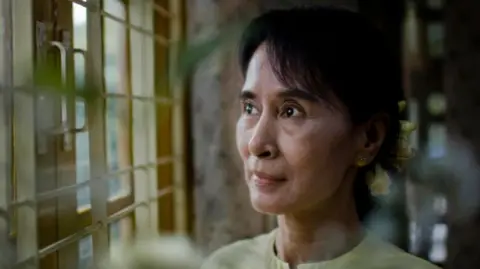 Aung San Suu Kyi looks out a window. 