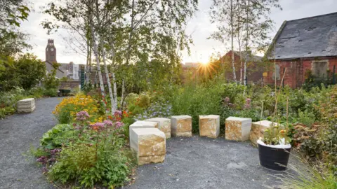 Britt Willoughby of the Core Arts garden A garden with shrubs in it and large stones