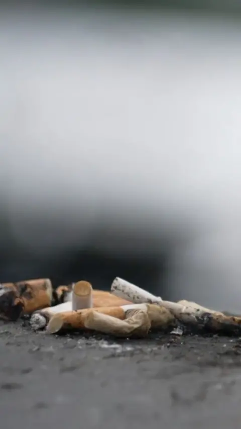 A close up image of a pile of burnt down cigarettes on the pavement.