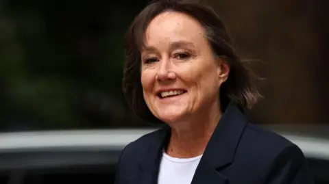 Jo Stevens arriving for a cabinet meeting at Downing Street. She is smiling and wearing a dark jacket over a white top. 