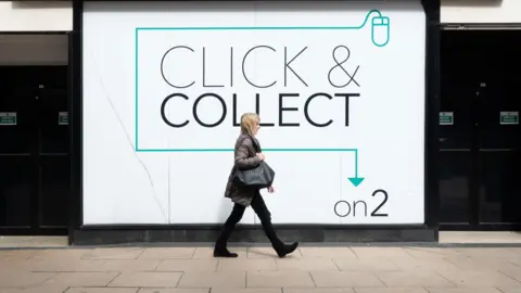 Alamy A female pedestrian walks in front of a click-and-collect point on the High Street.