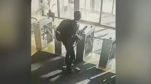 CCTV footage of a man with a gun seen by a security gate