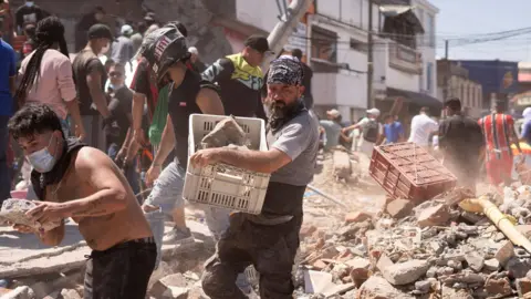 Residents dig through the debris of a collapsed building after an earthquake, in Cali, Colombia