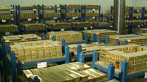 A picture of thousands of bars of gold bullion stacked on top of each other in a large room