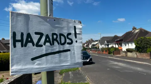 A sign saying "HAZARD" tied to a lampost 