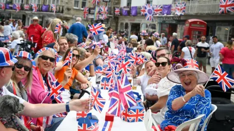 Getty Images People smile and wave union flags at a street party in Swanage