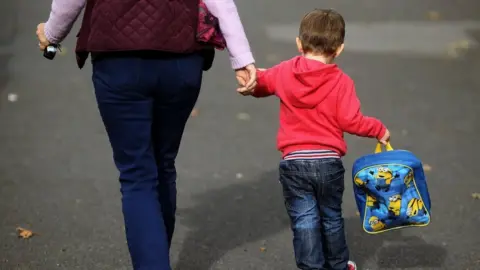 PA Media Woman holds child's hand