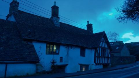 The Ancient Ram Inn seen from the outside at night