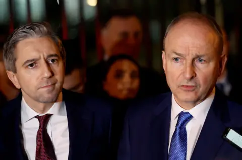 Simon Harris, left, and Micheál Martin right, are giving a press converence and both wearing suits and ties.