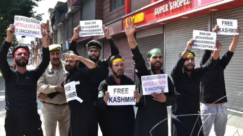 Getty Images A police officer tries to stop Kashmiri Shiite mourners from protesting during the procession. Authorities in parts of Srinagar imposed strict restrictions to prevent Shiite Muslims from taking part in Muharram procession.