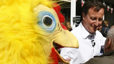 PA Media David Cameron with journalist Lee Cain, dressed as a chicken, Staffordshire, 2010