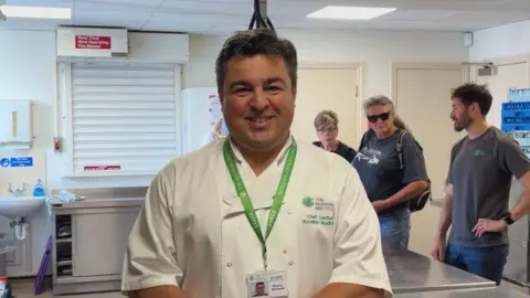 Chef wearing chef jacket stood in kitchen