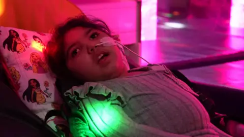 A picture of Sara looking up at the colourful lights in a sensory room at the Forget Me Not Children's Hospice in Huddersfield.