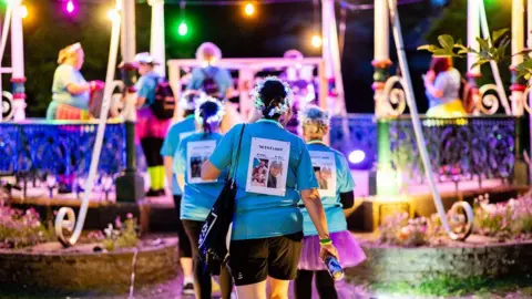 Prospect Hospice People dressed in bright colours walking to a bandstand with light
