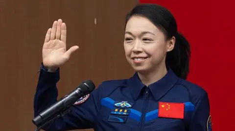 Hong Kong astronaut Li Jiaying wearing a deep blue space suit with a Chinese flag patch on her upper left chest