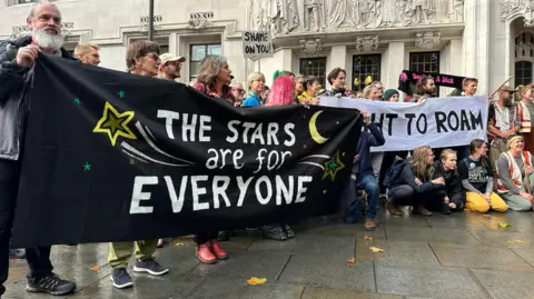 BBC Campaigners for wild camping hold a banner saying the Stars are for Everyne and Right to Roam and Shame on You outside the Supreme Court in London.