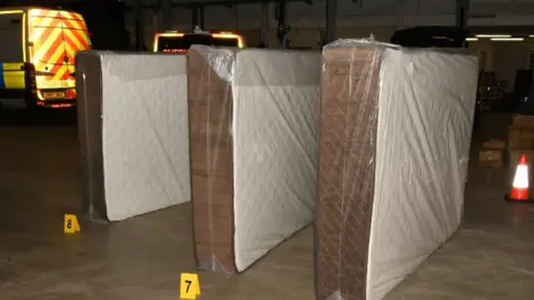 Three mattresses stood upright with yellow number markers by them on the ground after the police arrests