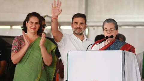 Getty Images Rahul Gandhi with sister Priyanka (left) and mother Sonia (right) addressing crowd in Rabareli  on 24 May 2024
