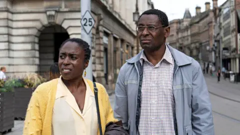 Pam and Dennis Bottomley, played by Sharlene Whyte and David Harewood, standing in a street