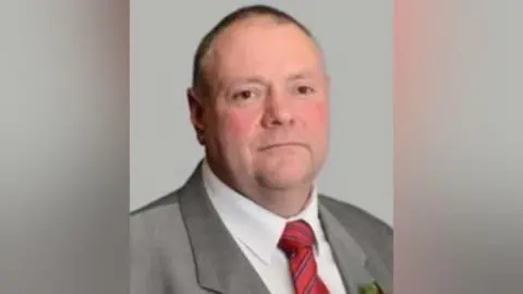 City of Wolverhampton Council A man in a grey suit and red tie is looking at the camera with a slight smile