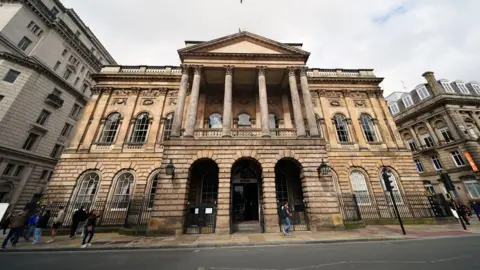 PA Media Street-level photograph of the front of Liverpool Town Hall. A few pedestrians are walking along the pavement.