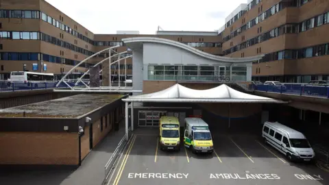 Queens Medical Centre (QMC) a light brick building with ambulances parked out the front