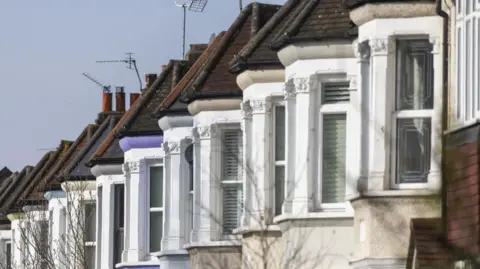 Getty Images Close up of the upper bay windows of a row of terraced houses in London. 