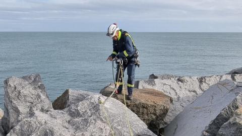 Coastguard training on rocks by the sea