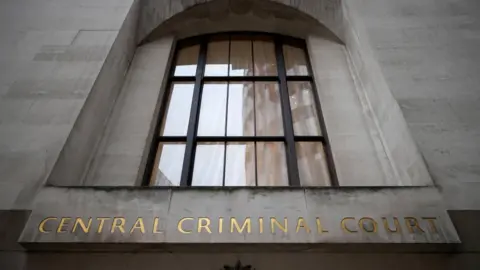 Letters in gold on the side of a grey stone building read 'Central Criminal Court'