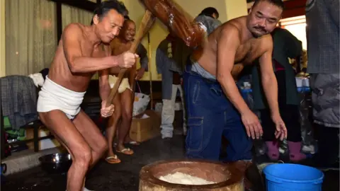 AFP Men in loincloths pounding rice