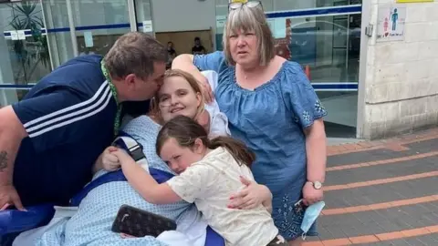 Day One Lucie Maguire outside hospital being hugged by family members