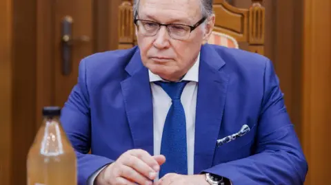 Moldovan Foreign Ministry A man in a blue jacket and tie stares at a dirty bottle of water