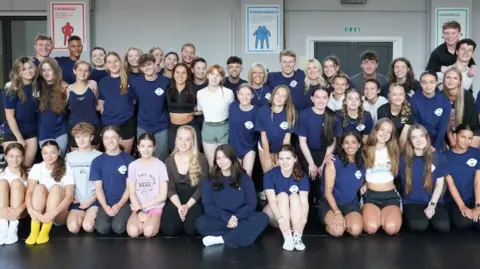 Studio H Photography About 40 dancers seated for a group shot in a dance hall