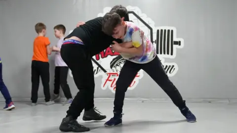 Daniel wrestles with another kid at a wrestling class