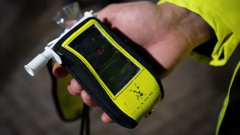 Getty Images A black and yellow device with a white nozzle on the left hand side, being held in a hand with a yellow sleeve
