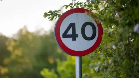 A 40 mph road circular sign. The outer edge is red while the inner circle is white with 40 in black numerals. 