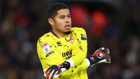 Goalkeeper Seny Dieng wearing yellow football kit and gloves. 