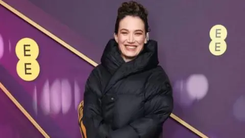 Getty Images Coralie Fargeat in a black puffa coat over her long, black outfit