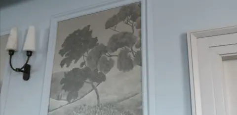 Wall panels in black and grey show a drawing on a tree.